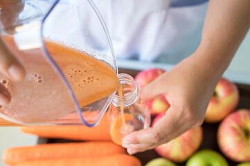Woman juicing cold pressed juice and pouring into bottle.Wellness food or detox smoothie.Vegetable...