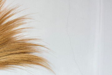Grass broom on white concrete wall. Household equipment.