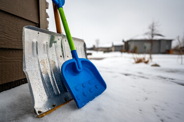 Adult and child snow shovel next to each other