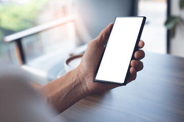 Mockup of man hand holding blank screen mobile smart phone in coffee shop