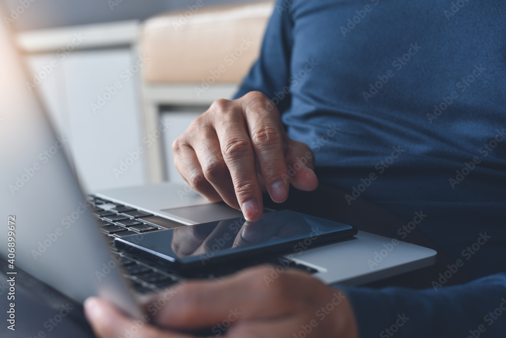 Poster work from home, casual man sitting on the floor using mobile phone during working on laptop computer