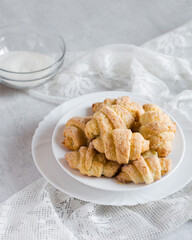 Homemade cottage cheese cookies bagels rogaliki with sugar on white plate on grey background, selective focus