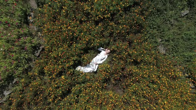 Girl in white dress laying in flowers closeup to wide angle view with spinning