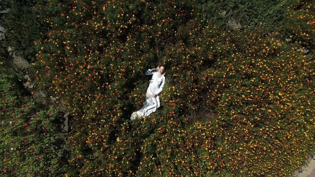 Girl in white dress laying in flowers closeup to wide angle view with spinning