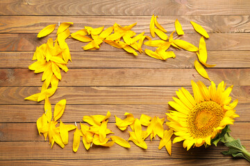 Frame made of sunflower petals on wooden background