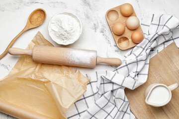 Fototapeta na wymiar Ingredients for dough and rolling pin on light background