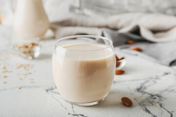 Glass of tasty vegan milk on light background