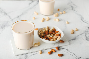 Glasses of tasty vegan milk on light background