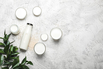 Bottles and glasses of rice milk on light background