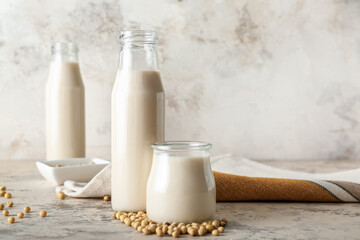 Bottles of tasty soy milk on light background