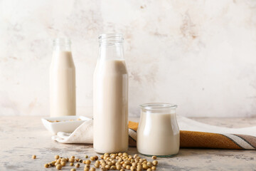 Bottles of tasty soy milk on light background