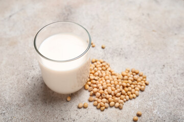 Glass of tasty soy milk on color background