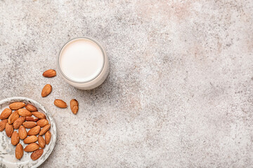 Glass of tasty almond milk on color background