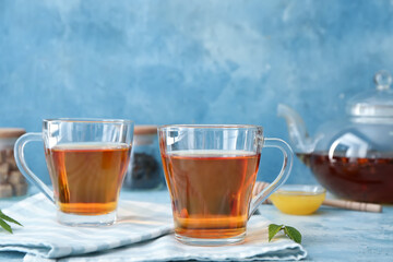 Cups of hot aromatic tea on color background