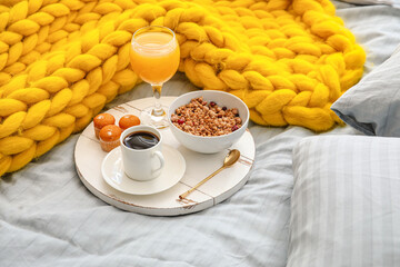 Tray with tasty breakfast on bed