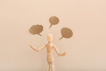 Wooden mannequin with empty speech bubbles on color background