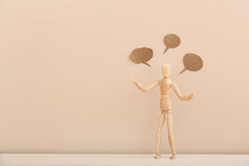 Wooden mannequin with empty speech bubbles on color background
