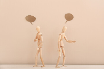 Wooden mannequins with empty speech bubbles on color background