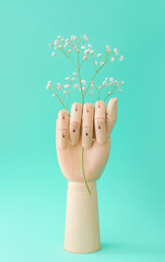 Wooden hand with flowers on color background