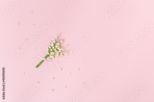 Small bouquet of lilies of the valley on soft pink background with free space for text. Concept of spring. Greeting card for birthday, mother's day, Valentines day.