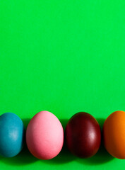 a row of four bright multicolored Easter eggs on green background on the bottom line, minimalistic design with shadows, creative template