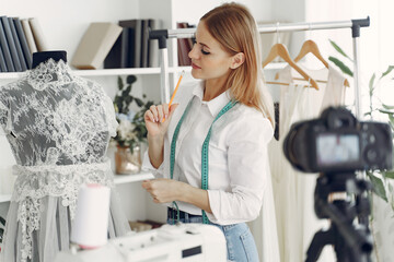 Woman creates clothes. Designer in a showroom. Blonde in a studio. Creator shooting a blog.