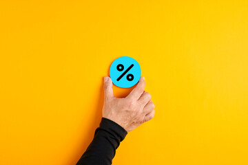 BMale hand placing a blue badge with a percent sign. Business discount, interest, mortgage or...