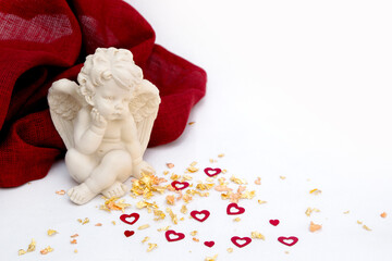 Valentine's Day. Angel on a white background with a red cloth, gold powder with hearts.