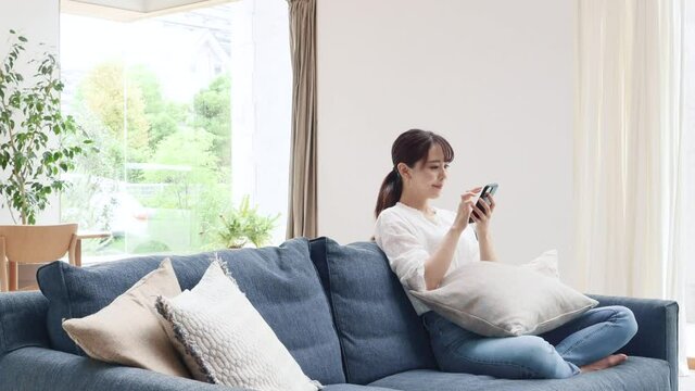 ソファーでスマホを使う女性