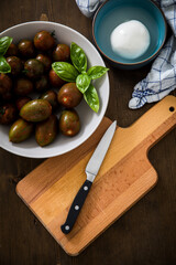 Gestreifte bunte Tiger Tomaten in Schale mit Mozzarella und Basilikum mit Geschirrtuch und Messer auf Holz Brett 