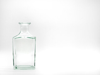 Single empty glass bottle on a white background. Transparent square bottle. Front view of the vertical staying colorless jar.