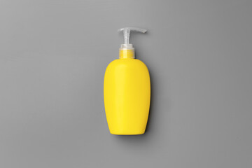 Yellow liquid detergents containers on gray background