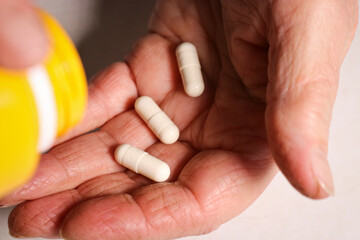 An elderly woman pours pills from a jar into her hand. Elderly health concept. Nursing and caring for elderly parents. Selective focus.