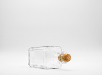 Empty glass bottle closed with cork cap isolated on a white background. Diagonal view of the laying...