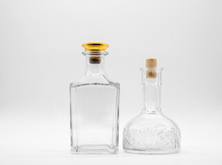 Empty glass carafe and empty glass bottle closed with corks isolated on a white background. Pair of the transparent bottles. Front view of the two vertical staying jars with different shape.