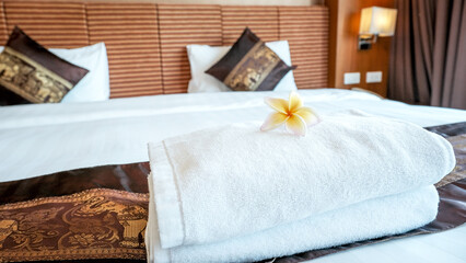 Fototapeta na wymiar Plumeria and towels on the bed in the luxury hotel room ready for tourist travel