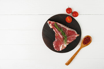 Raw t-bone steak on wooden cutting board on wooden table