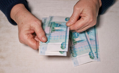 Senior woman counts one thousand rubles bills. Hands and money of the old woman. Old age, retirement savings and investment concept.