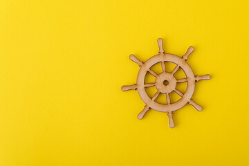 Wooden steering wheel on yellow background. Marine theme. Yacht management. Copy space