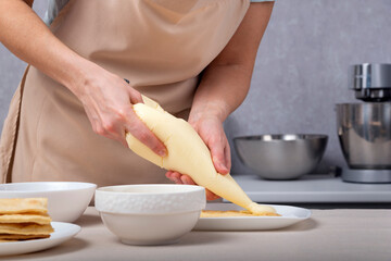 Pastry chef squeezes cream out of the culinary bag. Pastry bag. Cream injector. Culinary syringe