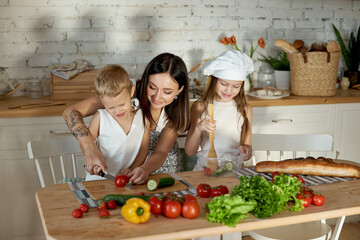 Mom cooks lunch with the kids. A woman teaches her daughter to cook from her son. Vegetarianism and healthy natural food