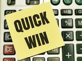 Text QUICK WIN written on yellow paper note on calculator.Business concept.