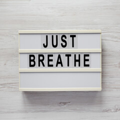 'Just breathe' on a lightbox on a white wooden surface, top view. Flat lay, overhead, from above.