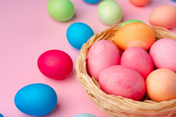 Painted Easter eggs in decorative nest on pink background