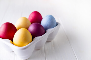 Multicolor eggs in a white tray. Minimal concept