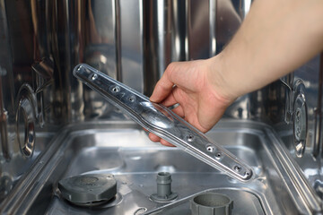 Man repairing a dishwasher with tools