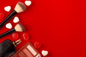 Obraz na płótnie Canvas Makeup products, eyeshadow palette, perfume and hearts on red background. Flat Lay. St.Valentine's Day Wallpaper.