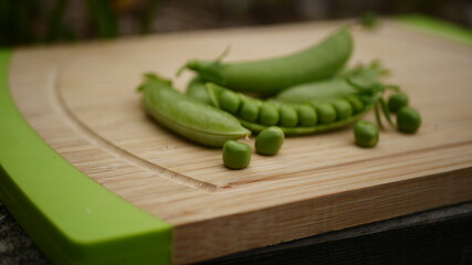 Chopping board with healthy organic peas in background