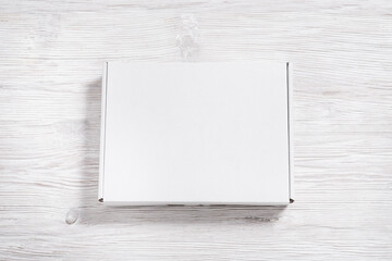 White cardboard carton box on wooden desk, flat lay mock up