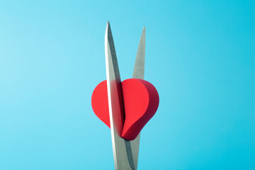Broken heart cut with scissors on a colored background. Unhappy love, betrayal, quarrel, breakup concept.